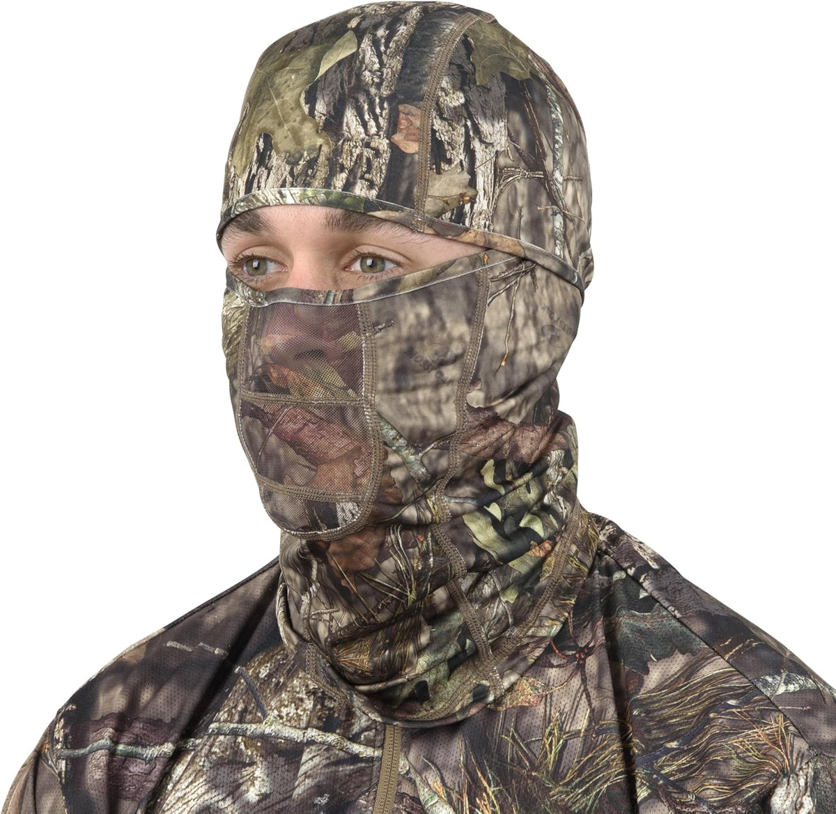 Person with camo gear aiming a rifle during hunting expedition in forest